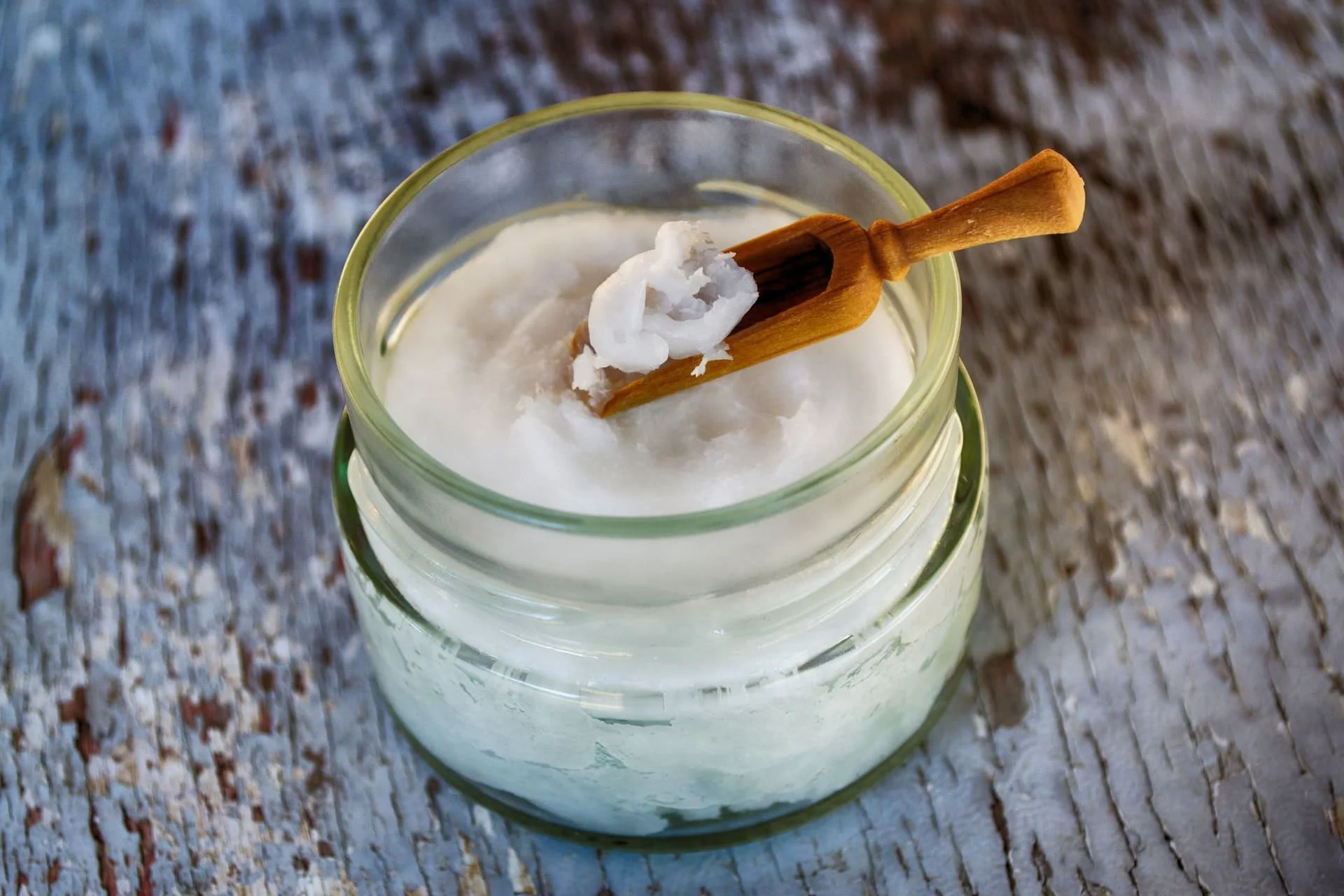 Coconut oil in a jar with a wooden measuring spoon